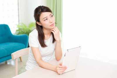 部屋でタブレットを見る女性